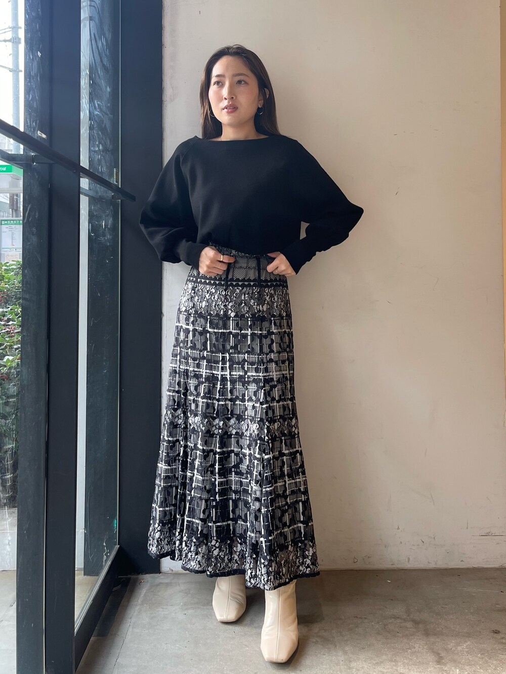 ブラック系のニット/セーター、ホワイト系のブーツ、ブラック系のスカートを着用したレディースの冬コーディネートの4枚目の写真