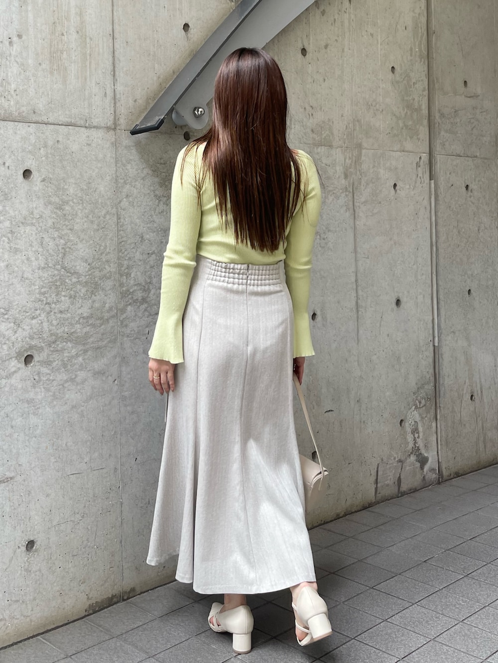 ホワイト系のショルダーバッグ、ホワイト系のパンプス、グレー系のスカートを着用したレディースの秋コーディネートの6枚目の写真