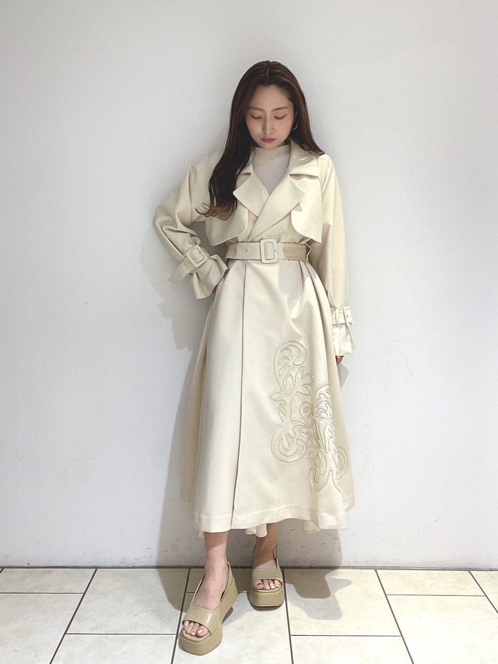 ホワイト系のトレンチコート、ベージュ系のサンダル、グリーン系のショルダーバッグを着用したレディースの冬コーディネートの6枚目の写真