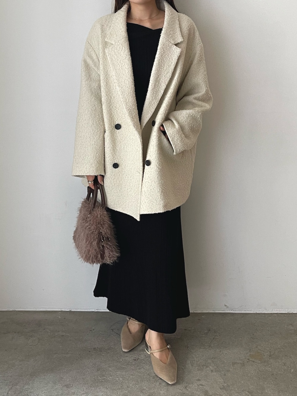 ブラック系のワンピース、ベージュ系のパンプス、ブラウン系のボストンバッグを着用したレディースの秋コーディネートの2枚目の写真