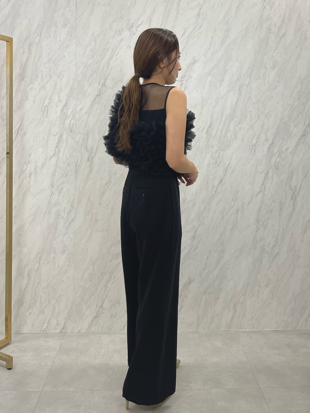 ブラック系のパンツドレス、ゴールド系のパンプスを着用したレディースの冬コーディネートの3枚目の写真