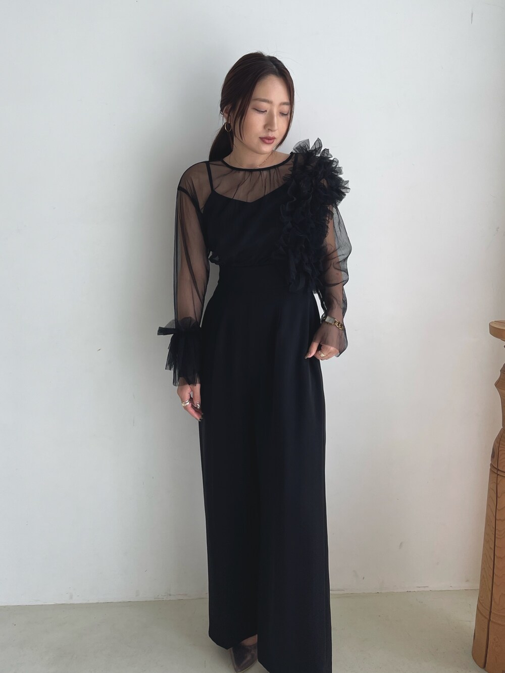 ブラック系のパンツドレス、シルバー系のパンプスを着用したレディースの秋コーディネートの8枚目の写真