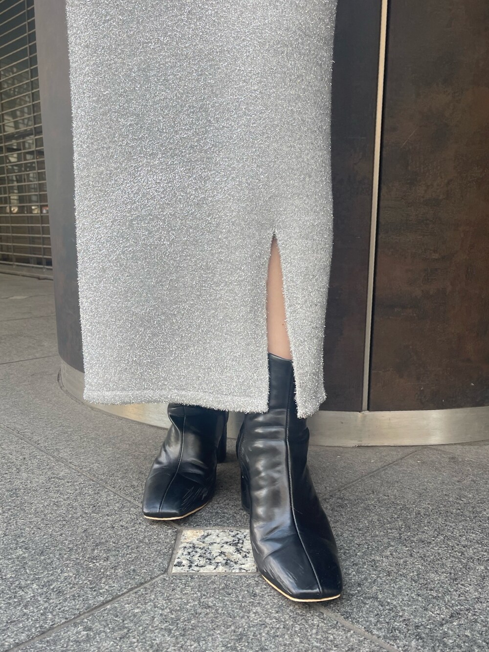 シルバー系のスカート、ブラック系のブーツ、グリーン系のニット/セーターを着用したレディースの冬コーディネートの7枚目の写真