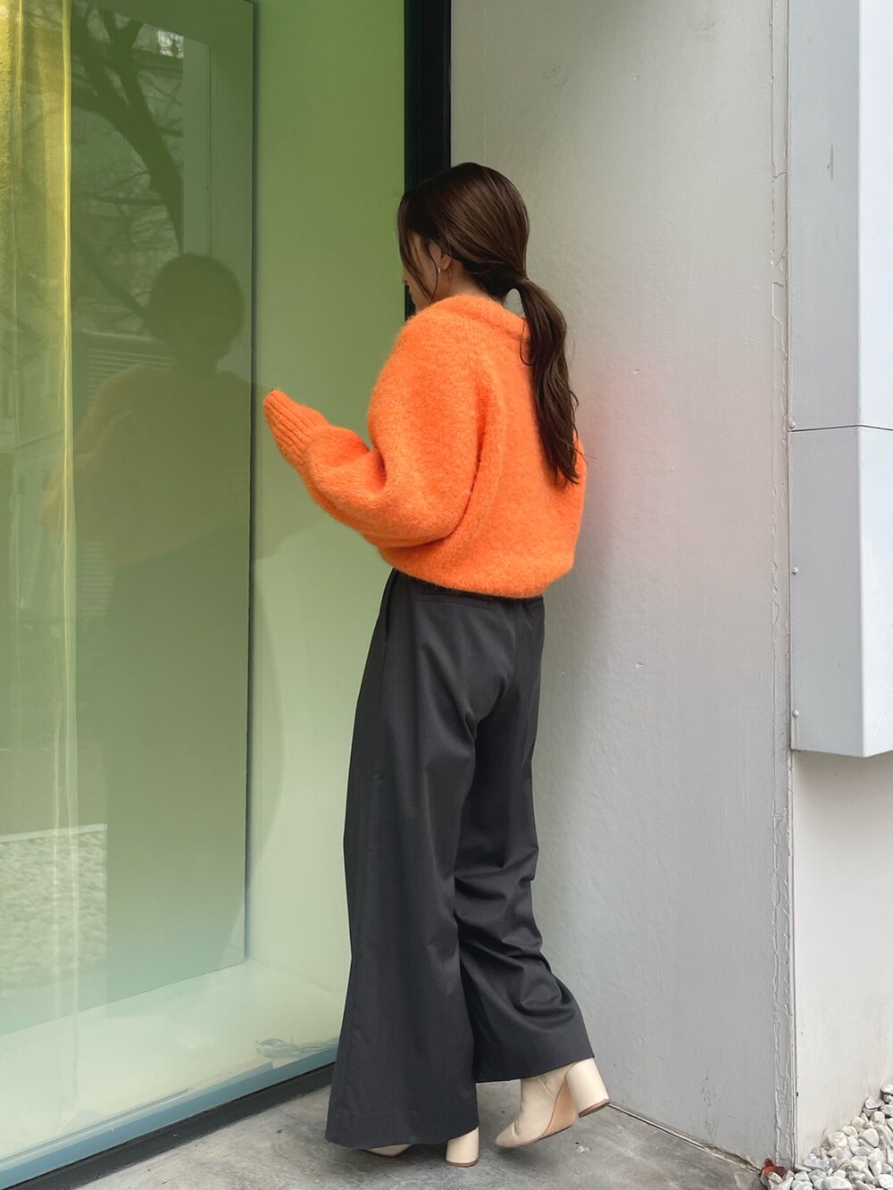 オレンジ系のニット/セーター、グレー系のその他パンツ、ホワイト系のブーツを着用したレディースの冬コーディネートの8枚目の写真
