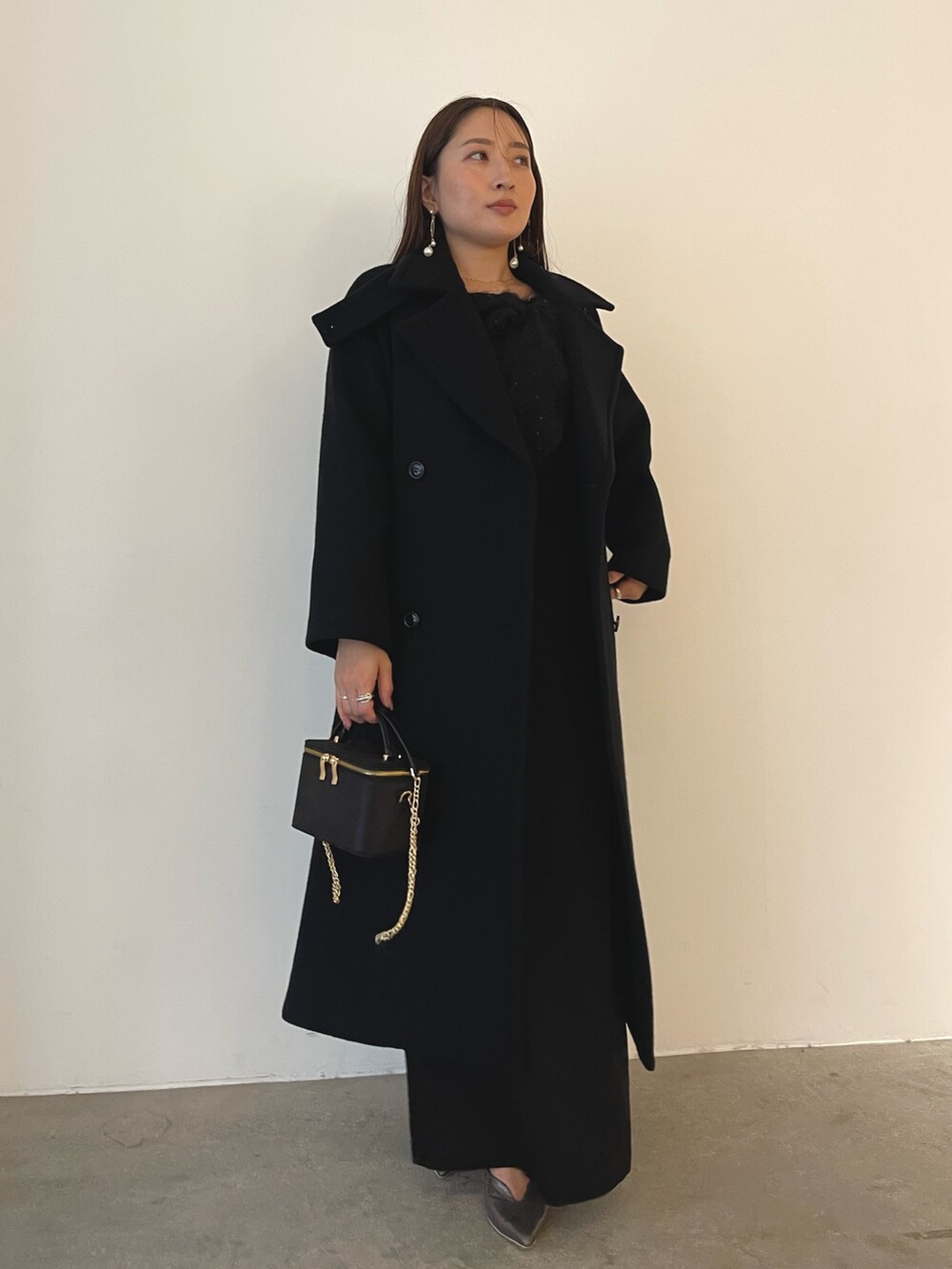 シルバー系のパンプス、ブラック系のハンドバッグ、ブラック系のドレスを着用したレディースの秋コーディネートの5枚目の写真