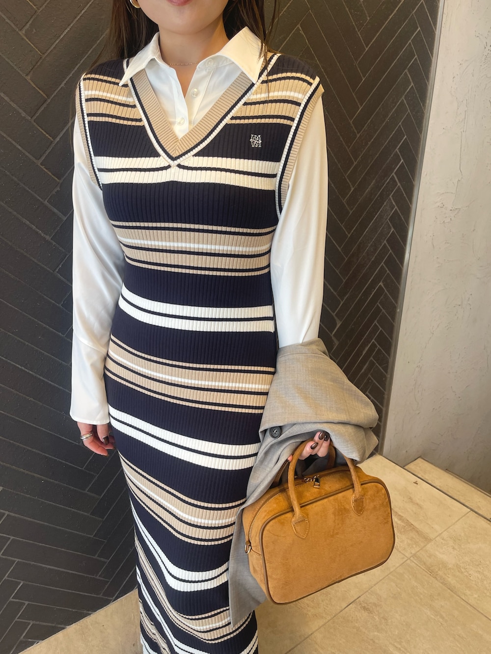 イエロー系のハンドバッグ、ベージュ系のブーツ、グレー系のテーラードジャケットを着用したレディースの冬コーディネートの8枚目の写真