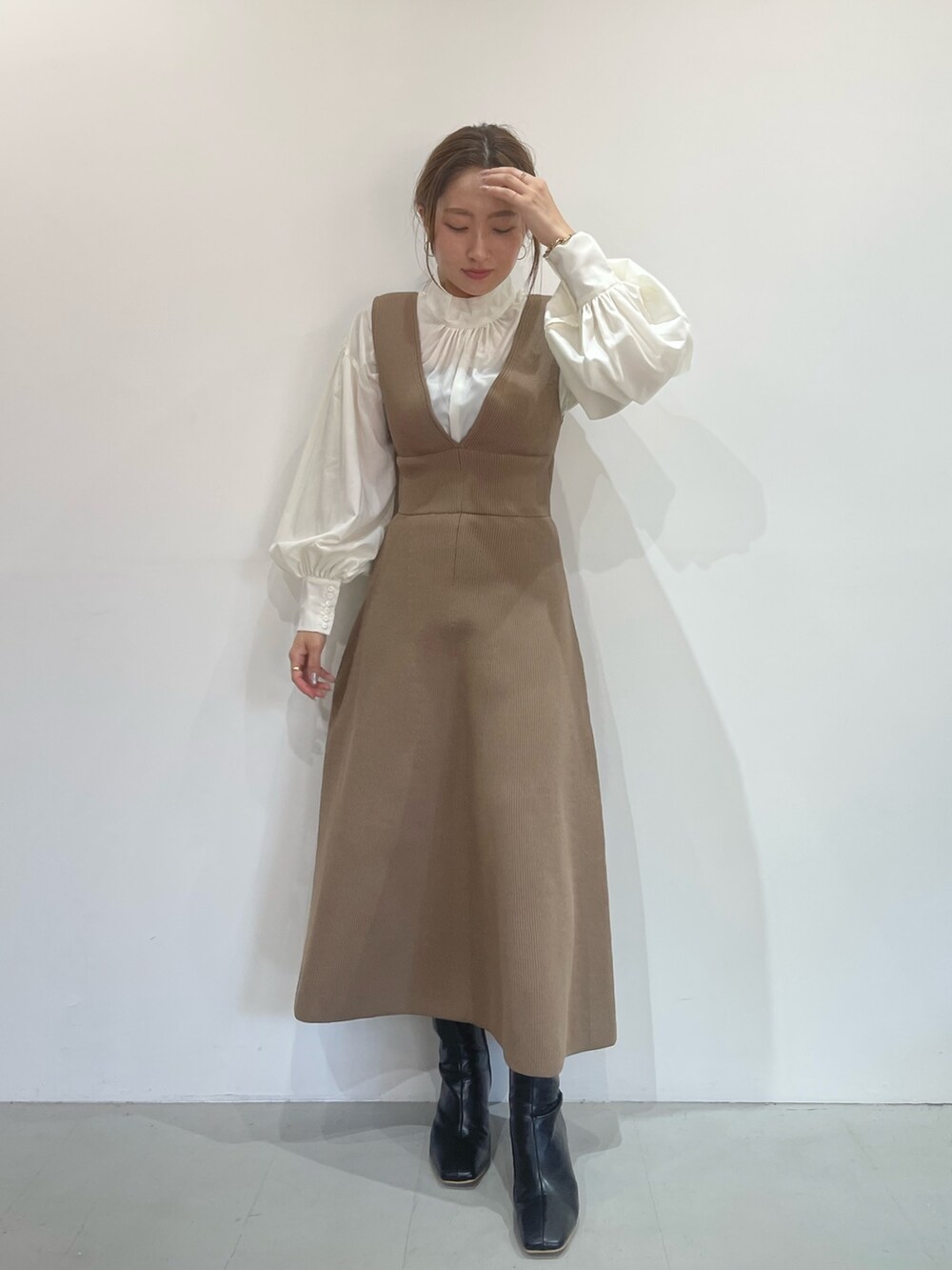 ブラック系のブーツ、ベージュ系のジャンパースカート、ホワイト系のシャツ/ブラウスを着用したレディースの秋コーディネートの2枚目の写真