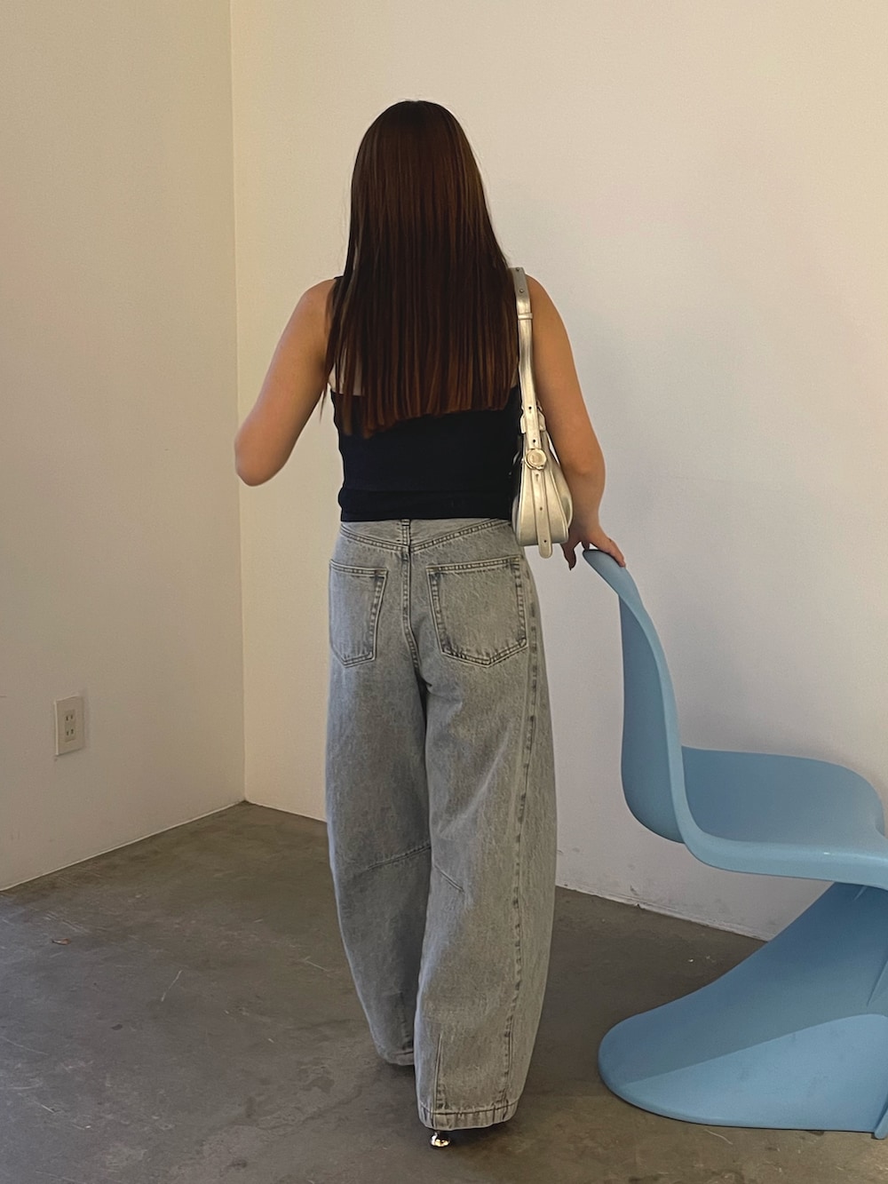 ブルー系のデニムパンツ、シルバー系のハンドバッグ、ブラウン系のサンダルを着用したレディースの春コーディネートの5枚目の写真