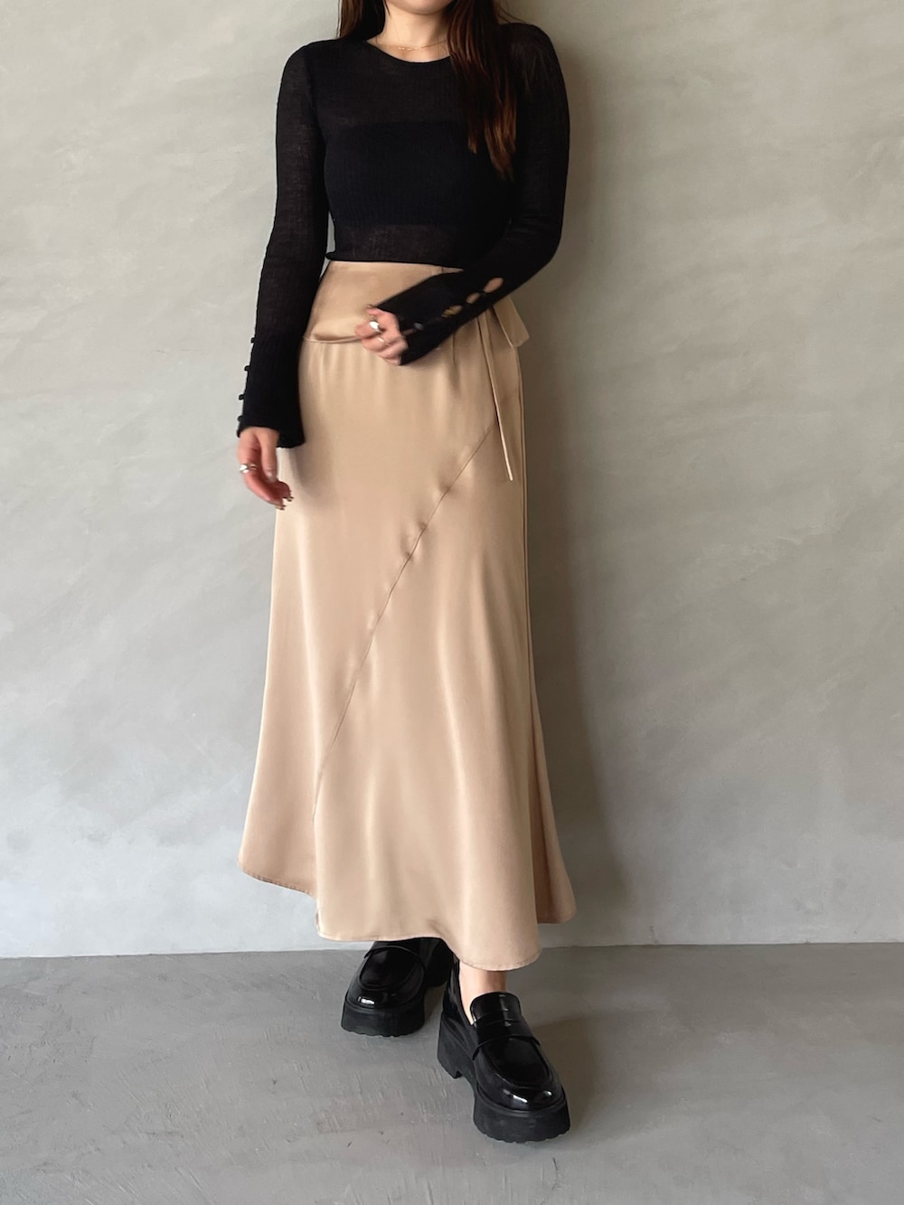 ベージュ系のスカート、ブラック系のニット/セーターを着用したレディースの夏コーディネートの3枚目の写真