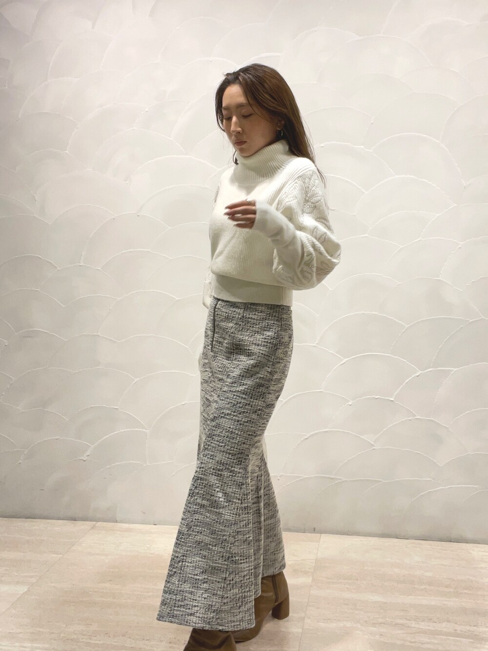 ホワイト系のニット/セーター、ブラック系のスカート、ベージュ系のブーツを着用したレディースの秋コーディネートの4枚目の写真