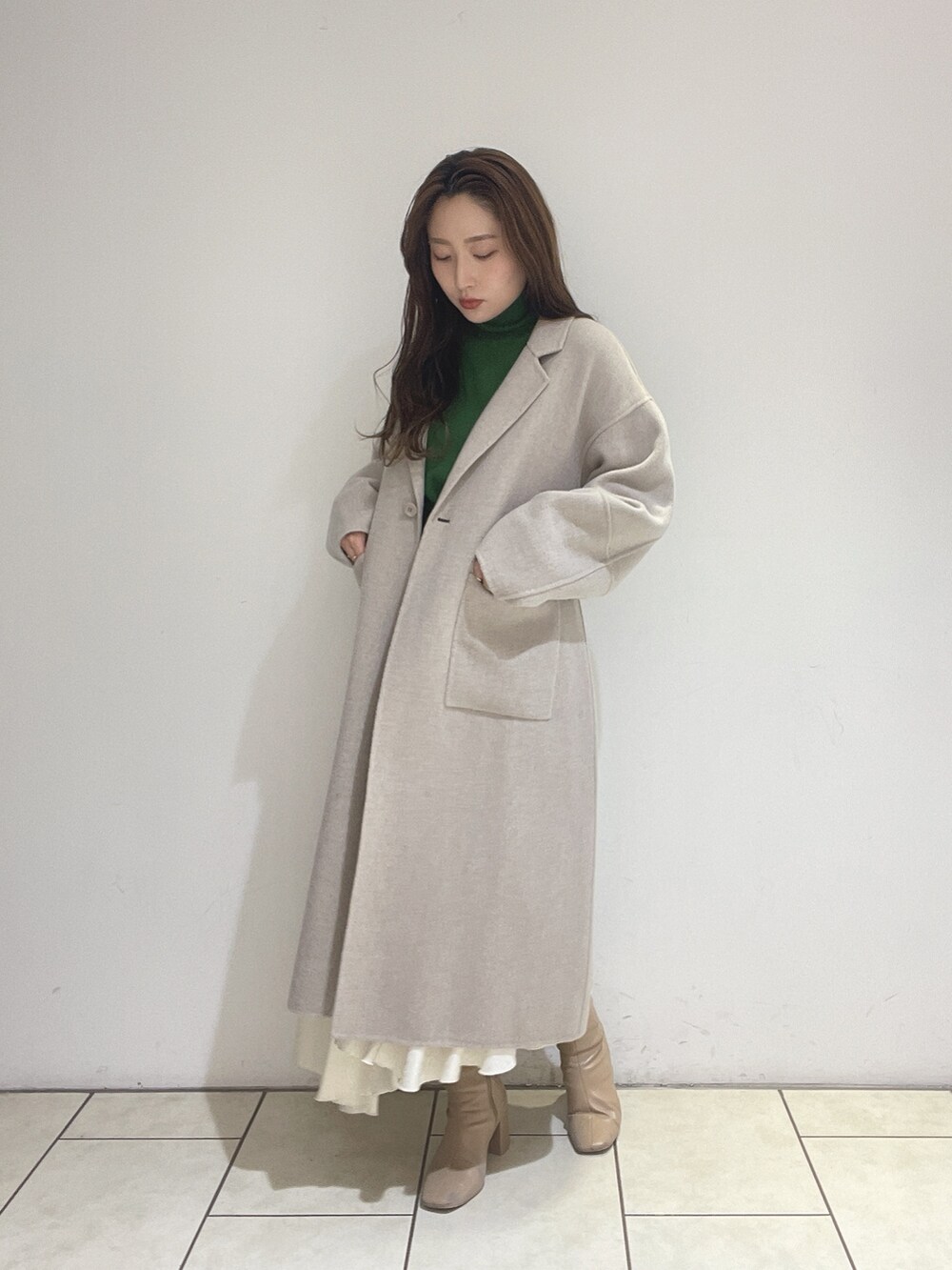 ホワイト系のスカート、ベージュ系のその他アウター、グリーン系のニット/セーターを着用したレディースの冬コーディネートの4枚目の写真