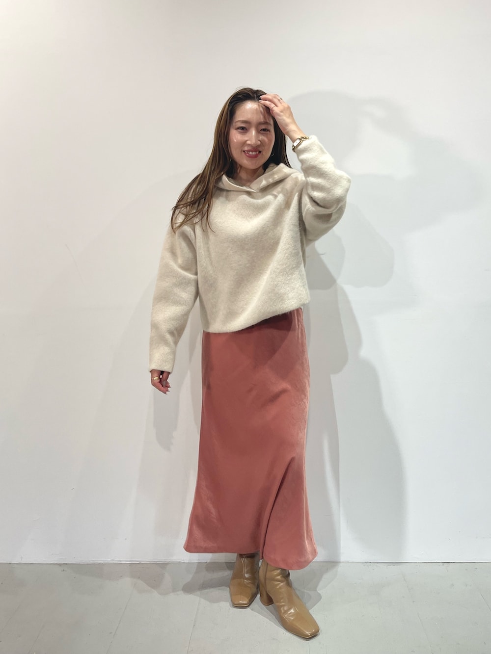 ピンク系のスカート、ベージュ系のブーツ、ホワイト系のパーカーを着用したレディースの夏コーディネートの3枚目の写真