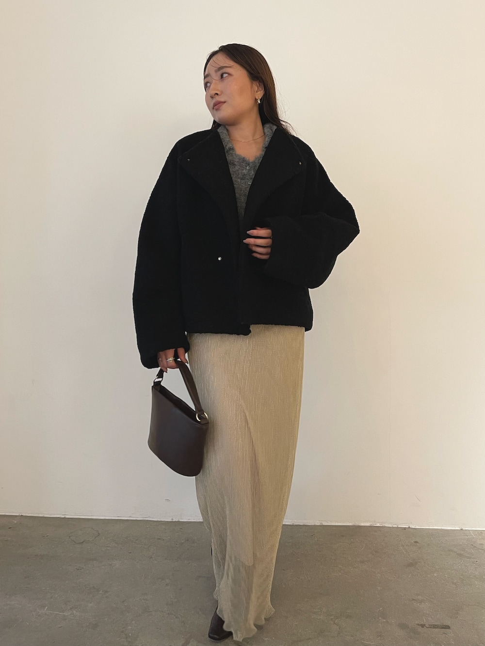 ブラック系のブルゾン、ブラウン系のハンドバッグ、ブラウン系のブーツを着用したレディースの秋コーディネートの2枚目の写真