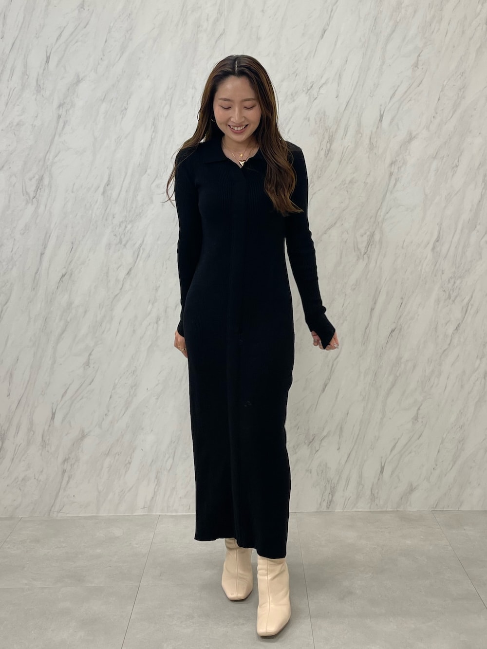 ブラック系のワンピース、ホワイト系のブーツ、ゴールド系のネックレスを着用したレディースの冬コーディネートの3枚目の写真