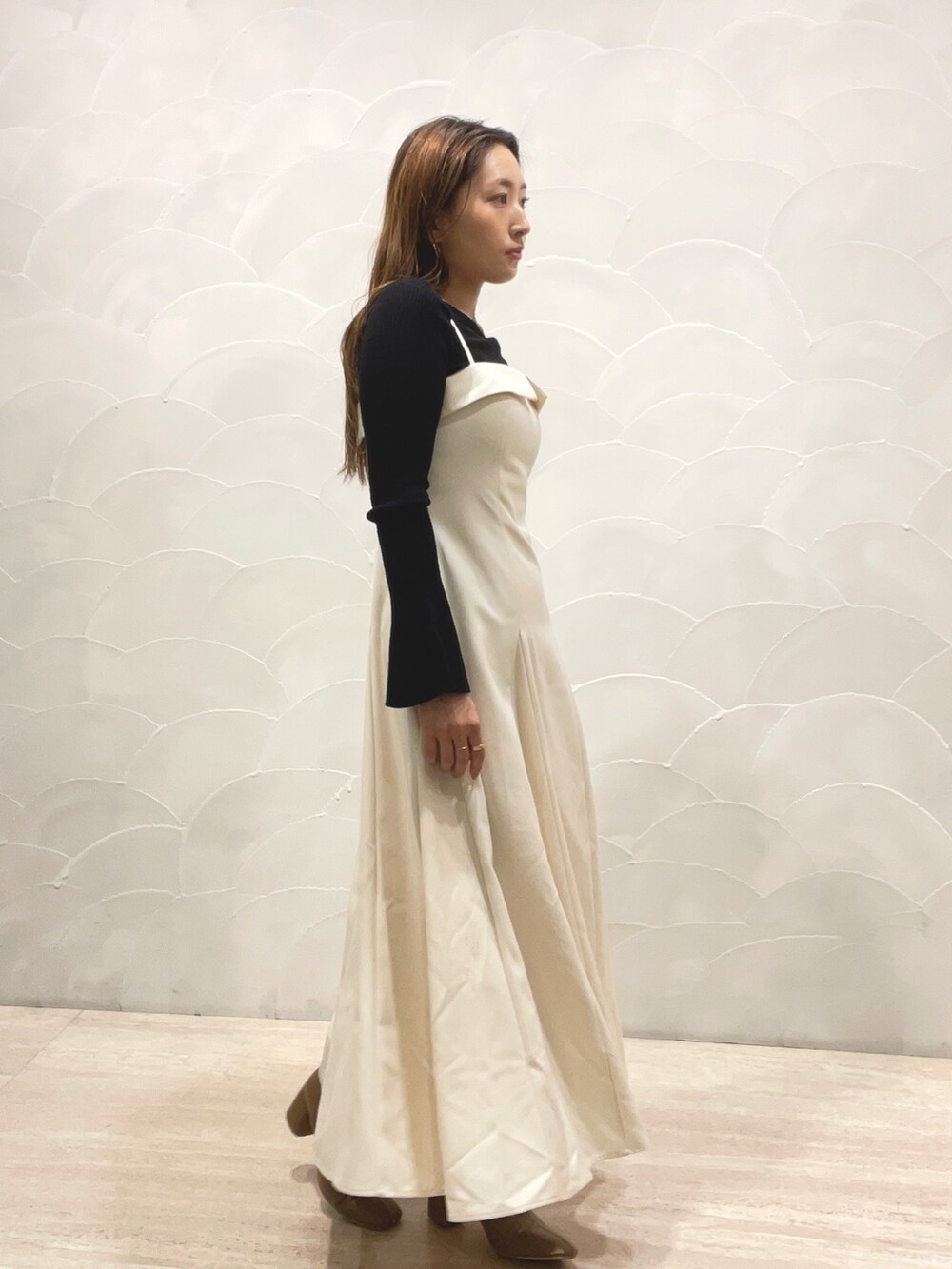 ベージュ系のブーツ、ブラック系のニット/セーター、ホワイト系のワンピースを着用したレディースの秋コーディネートの2枚目の写真