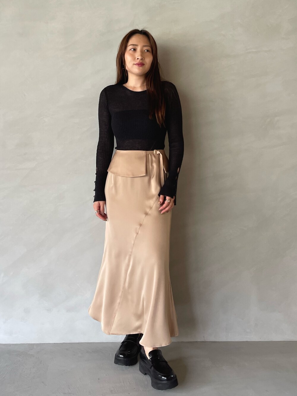 ベージュ系のスカート、ブラック系のニット/セーターを着用したレディースの夏コーディネートの2枚目の写真