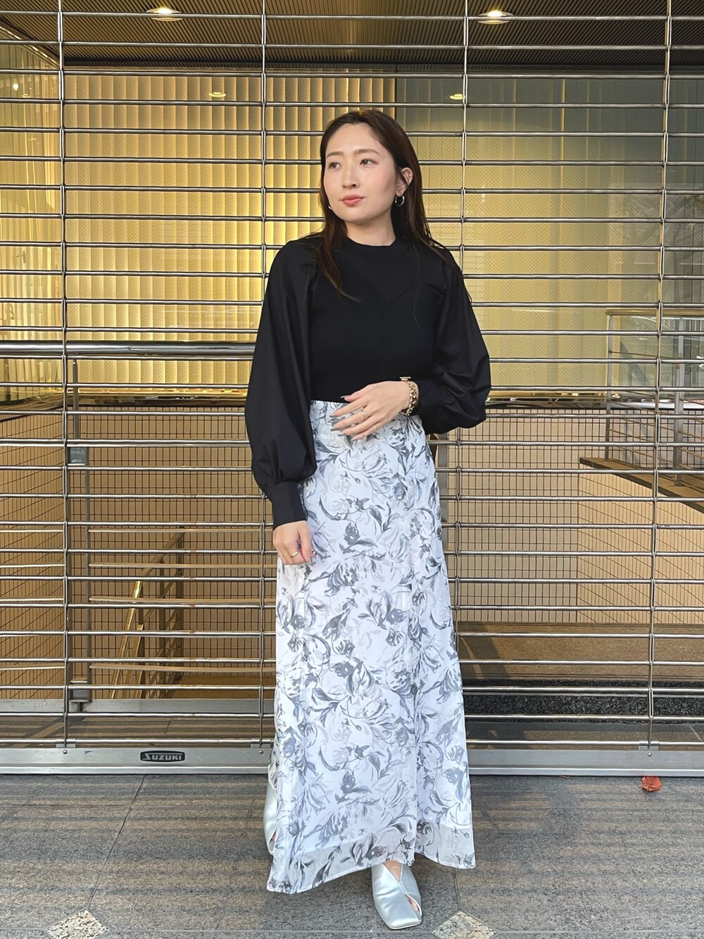 グレー系のスカート、シルバー系のパンプス、ブラック系のニット/セーターを着用したレディースの冬コーディネートの2枚目の写真