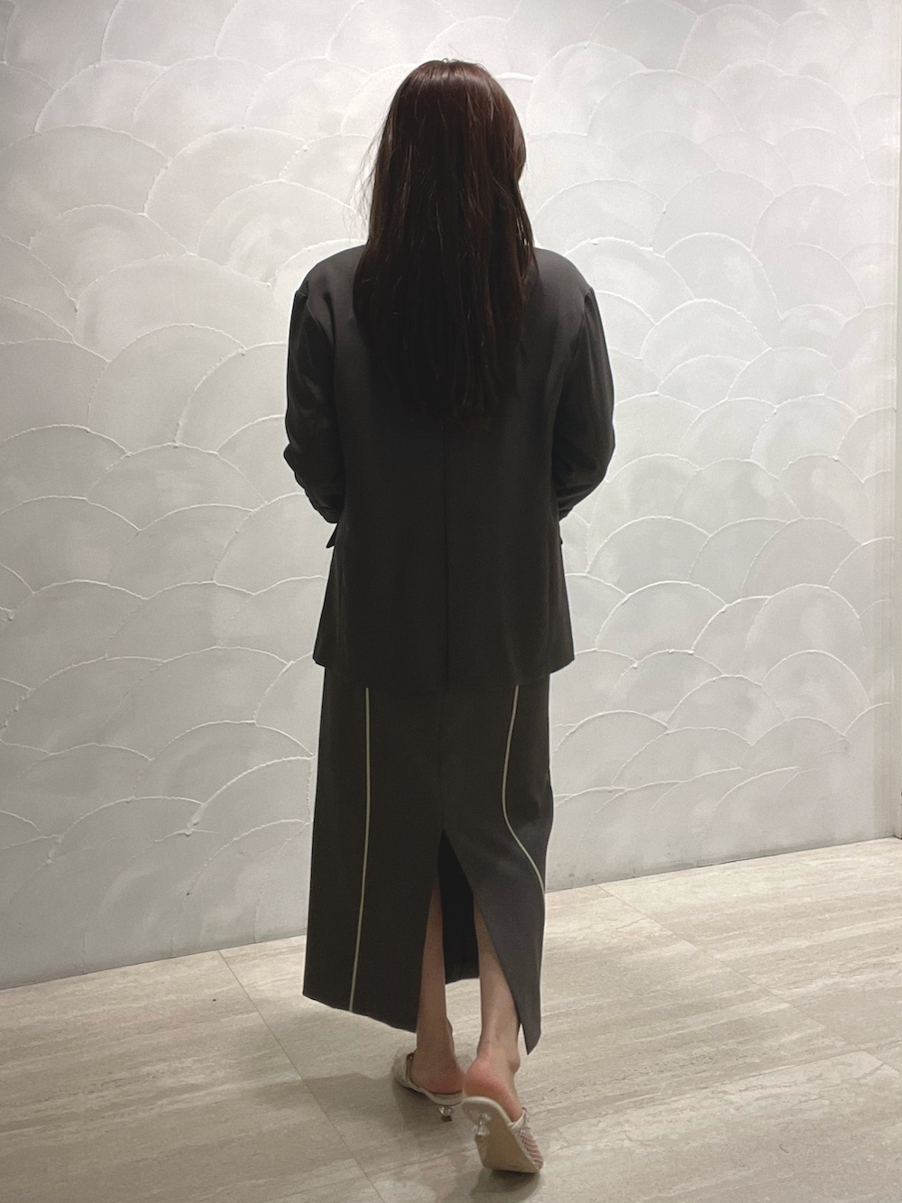 グレー系のスカート、ホワイト系のサンダル、グレー系のニット/セーターを着用したレディースの春コーディネートの5枚目の写真