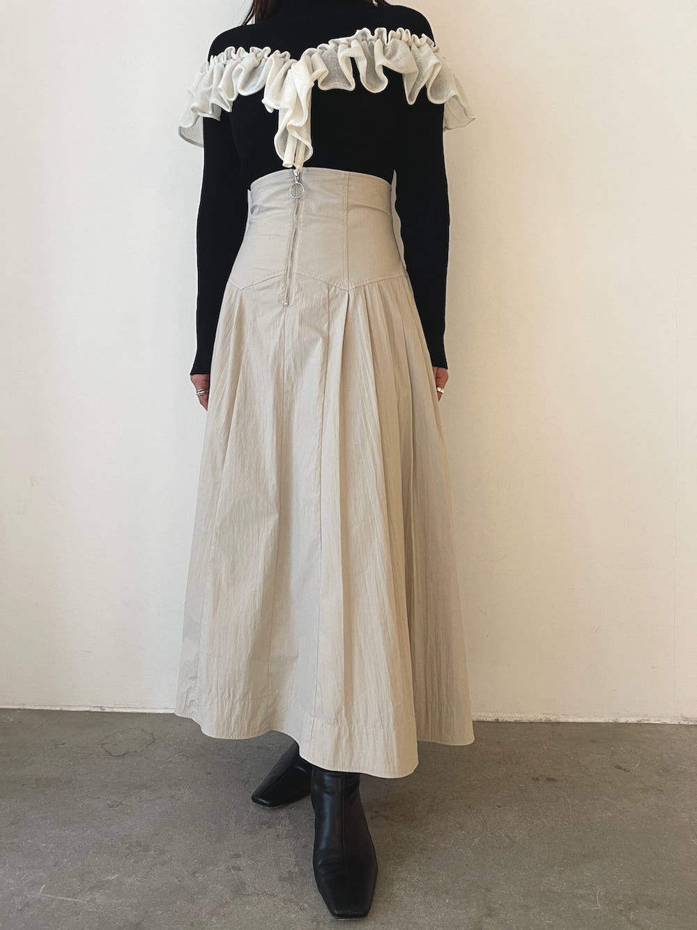 ブラック系のブーツ、ホワイト系のスカート、ブラック系のニット/セーターを着用したレディースの秋コーディネートの8枚目の写真