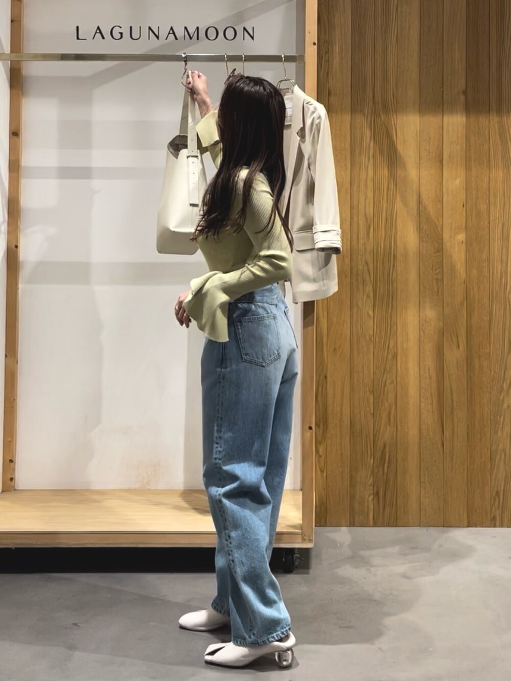 グリーン系のニット/セーター、ホワイト系のパンプス、ブルー系のデニムパンツを着用したレディースの冬コーディネートの4枚目の写真