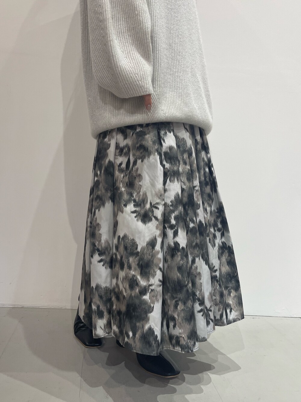 ブラック系のスカート、ブラック系のブーツ、ホワイト系のニット/セーターを着用したレディースの夏コーディネートの6枚目の写真