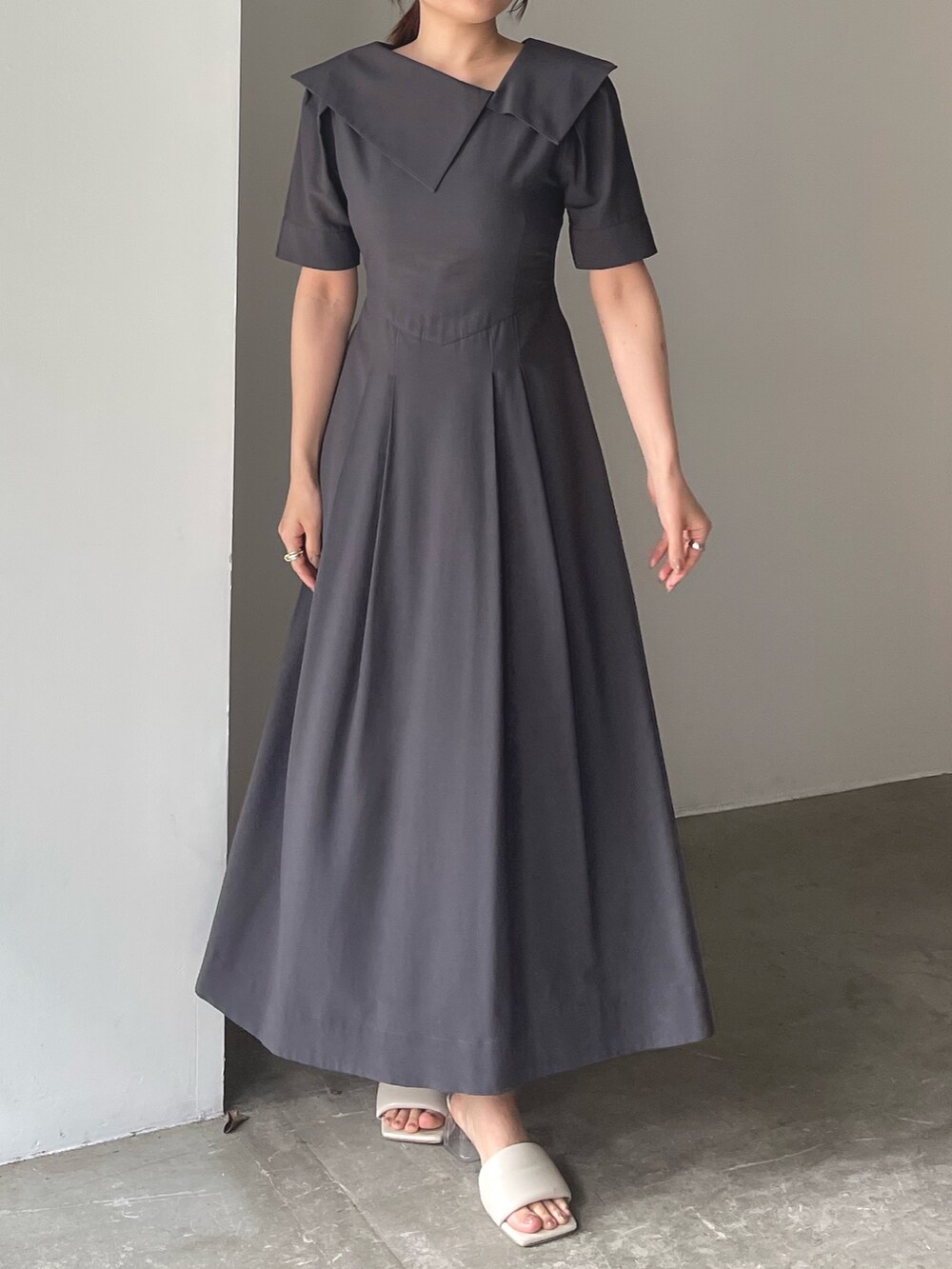 ホワイト系のサンダル、グレー系のワンピース、ゴールド系のピアス（両耳用）を着用したレディースの春コーディネートの3枚目の写真