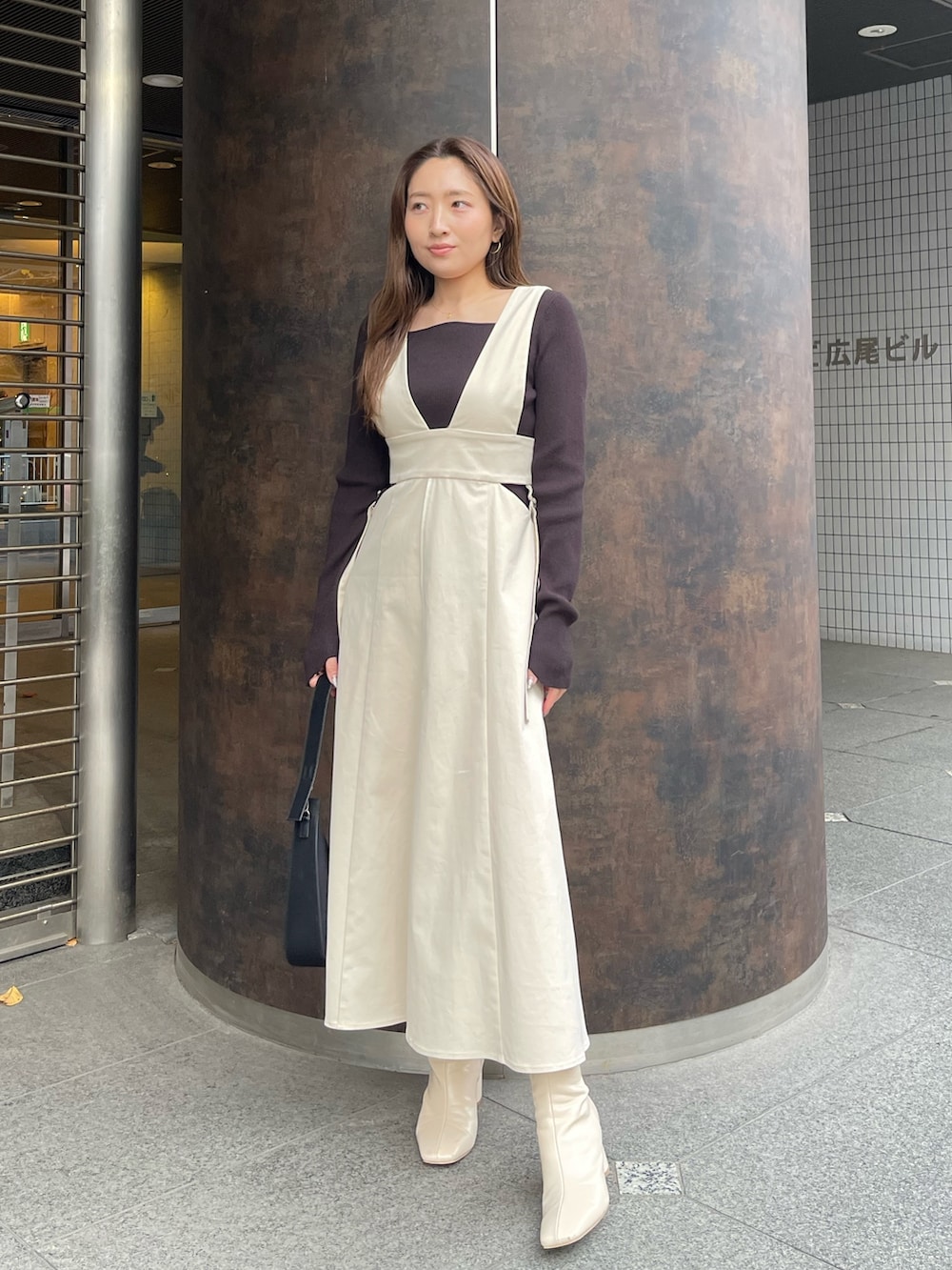 ホワイト系のブーツ、ホワイト系のジャンパースカート、ブラック系のニット/セーターを着用したレディースの冬コーディネートの3枚目の写真