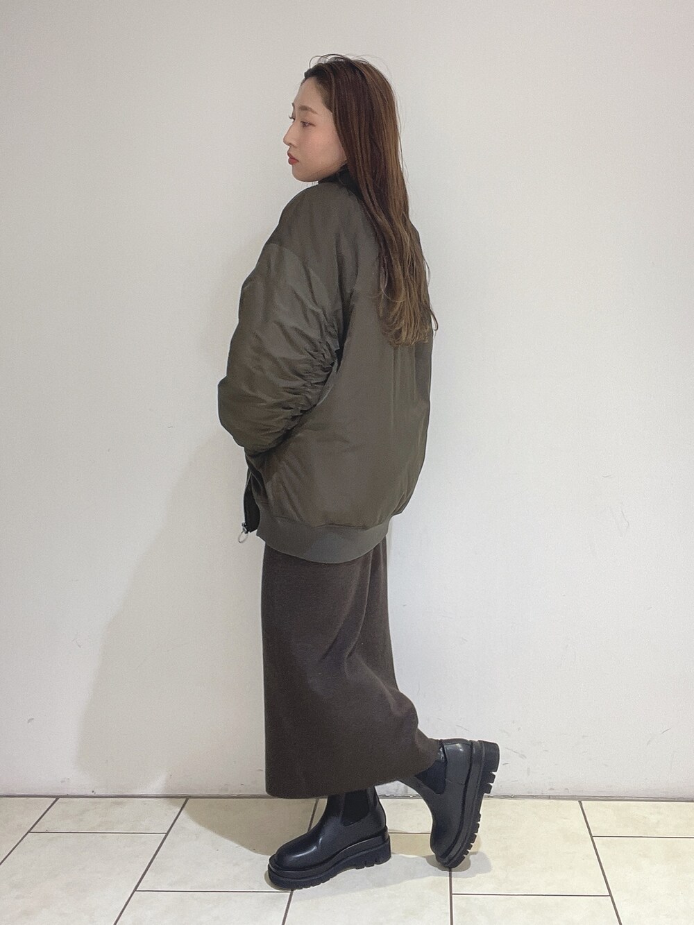 ブラウン系のニット/セーター、ブラウン系のスカート、ブラック系のブーツを着用したレディースの冬コーディネートの6枚目の写真