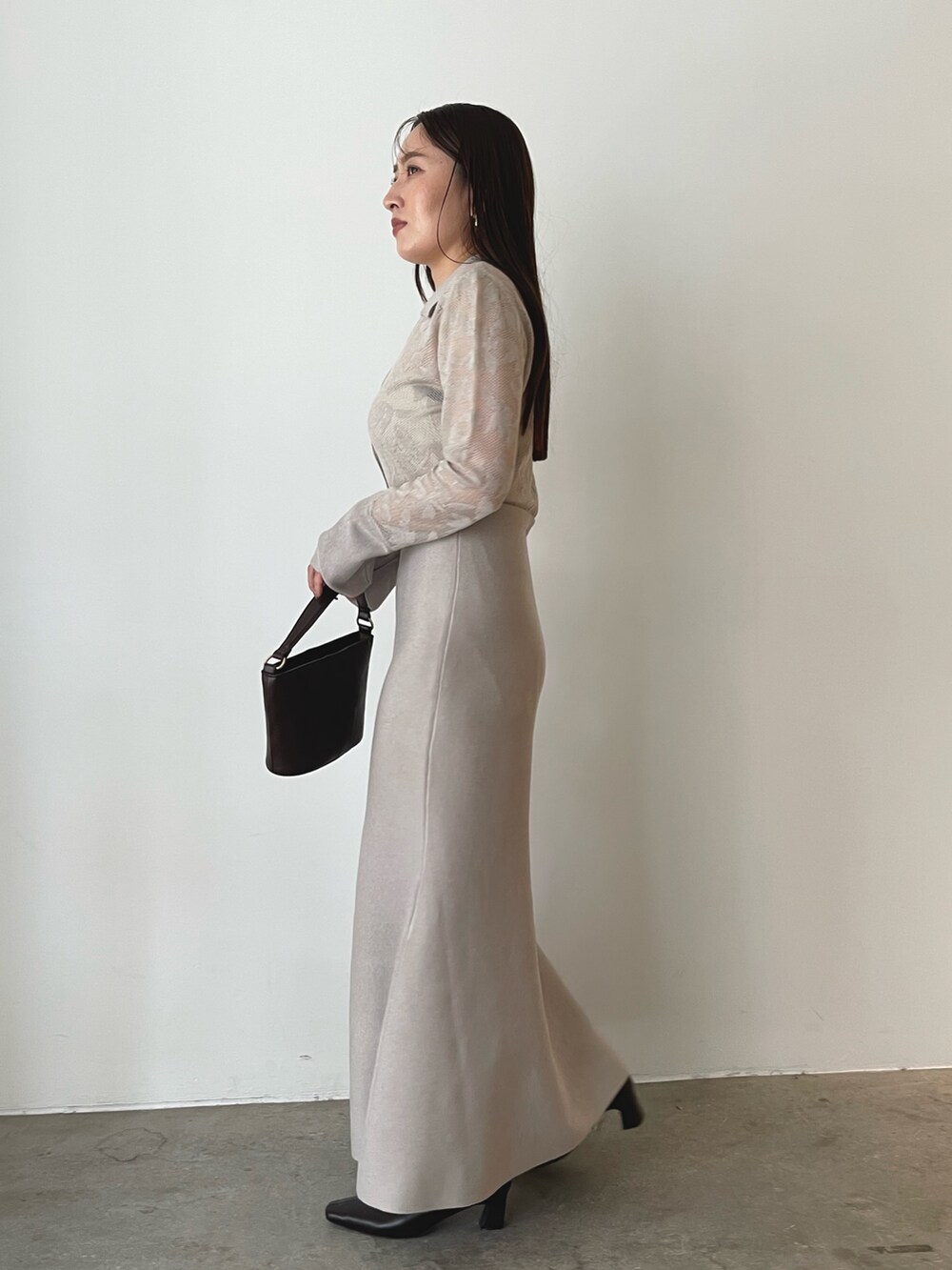ブラウン系のハンドバッグ、ベージュ系のワンピース、ブラウン系のブーツを着用したレディースの秋コーディネートの4枚目の写真