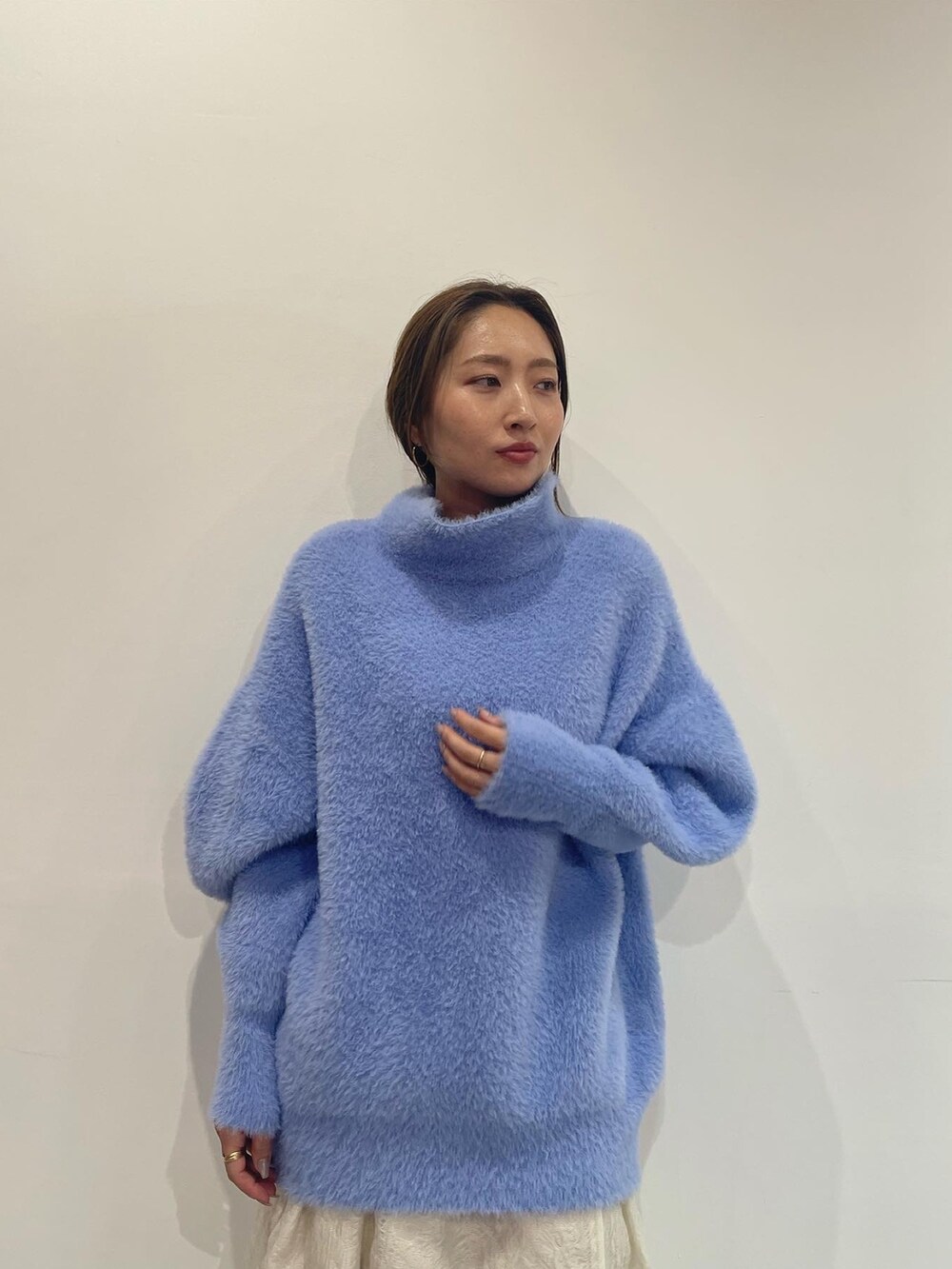 ブルー系のニット/セーター、ベージュ系のブーツ、ホワイト系のスカートを着用したレディースの秋コーディネートの6枚目の写真