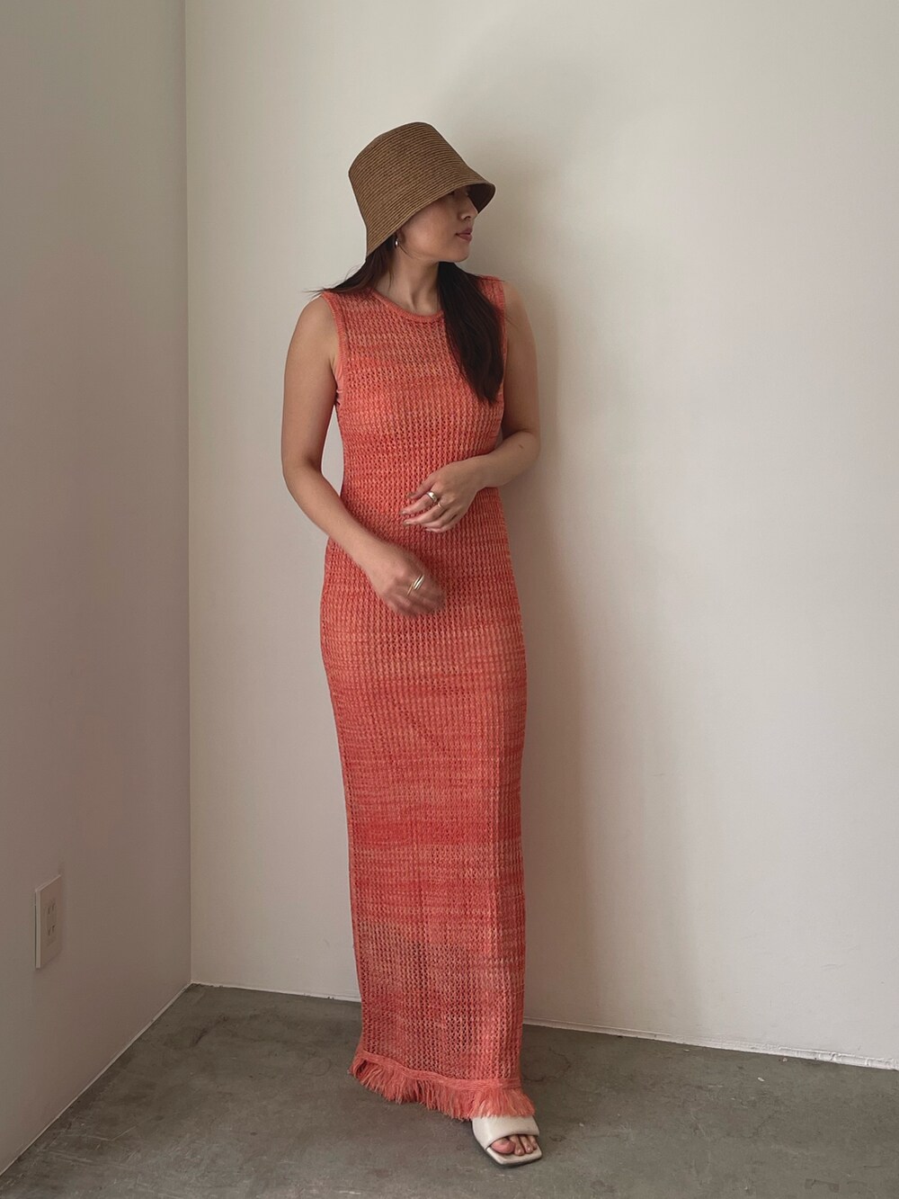 ホワイト系のサンダル、オレンジ系のワンピース、ブラウン系のハットを着用したレディースの春コーディネートの6枚目の写真