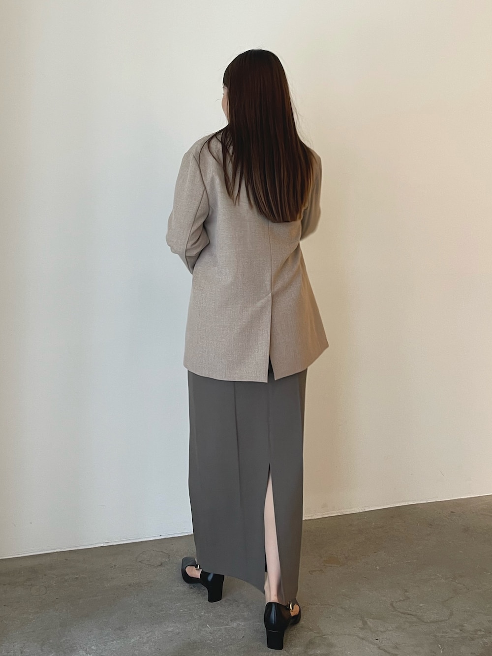 ブラック系のパンプス、グレー系のスカート、ベージュ系のニット/セーターを着用したレディースの秋コーディネートの5枚目の写真