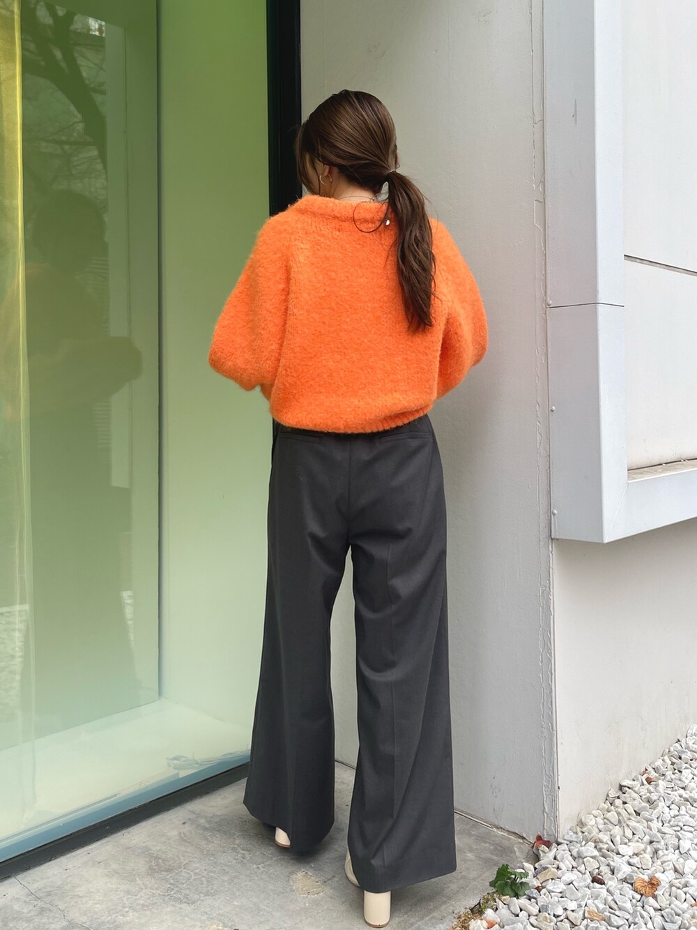オレンジ系のニット/セーター、グレー系のその他パンツ、ホワイト系のブーツを着用したレディースの冬コーディネートの7枚目の写真