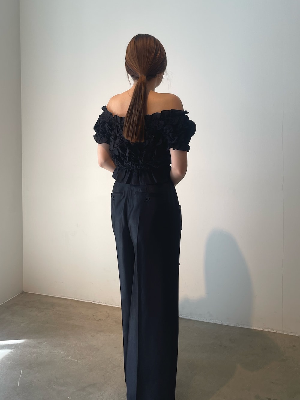 ブラック系のハンドバッグ、ゴールド系のパンプス、ブラック系のパンツドレスを着用したレディースの春コーディネートの6枚目の写真