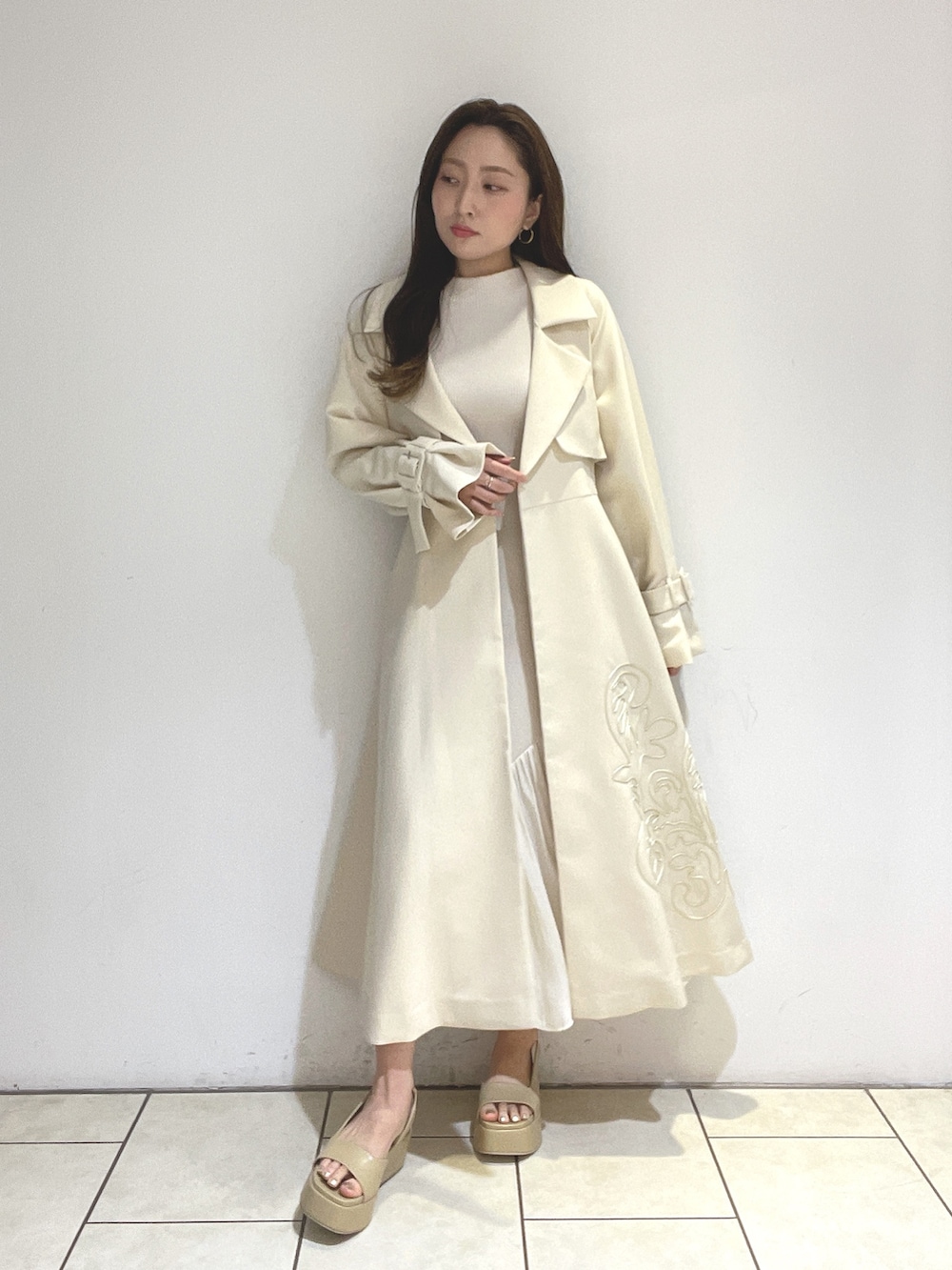 ホワイト系のトレンチコート、ベージュ系のサンダル、グリーン系のショルダーバッグを着用したレディースの冬コーディネートの9枚目の写真