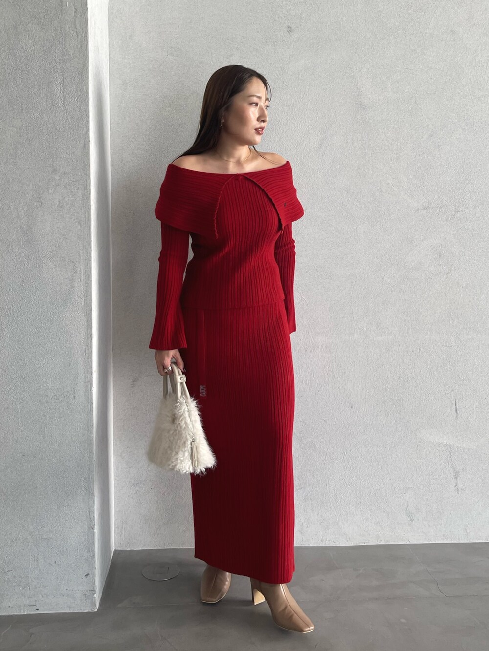 レッド系のニット/セーター、ベージュ系のブーツ、レッド系のスカートを着用したレディースの秋コーディネートの5枚目の写真