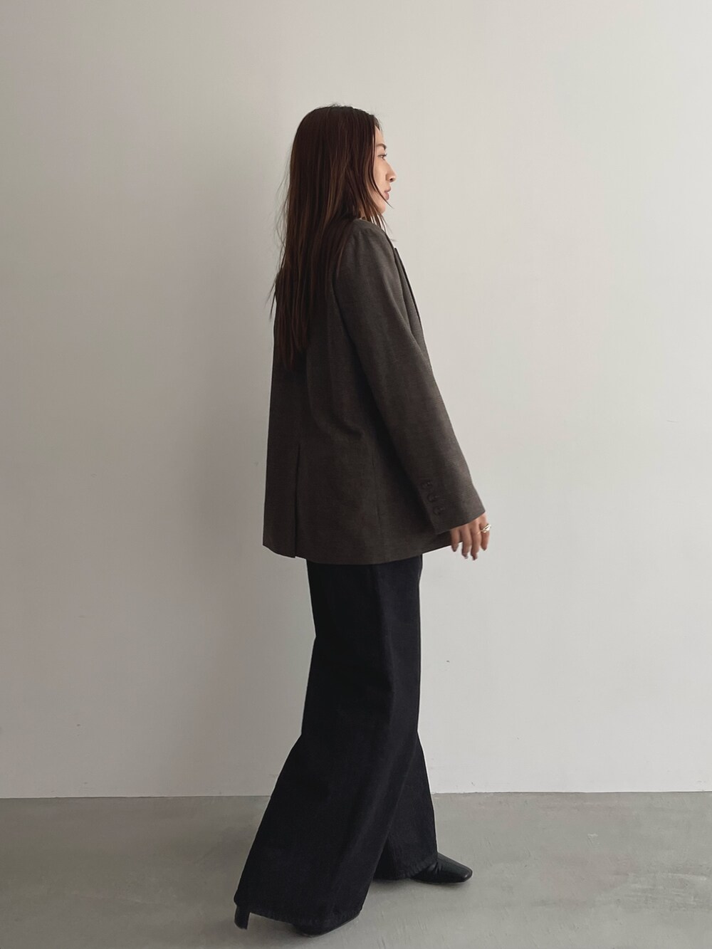 ブラック系のデニムパンツ、グレー系のニット/セーター、ブラウン系のテーラードジャケットを着用したレディースの夏コーディネートの4枚目の写真