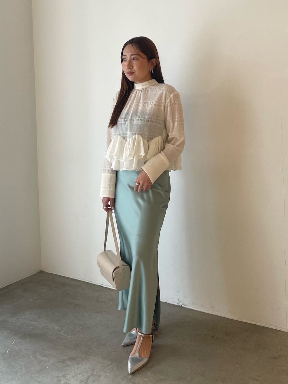 シルバー系のパンプス、ホワイト系のシャツ/ブラウス、グリーン系のスカートを着用したレディースの冬コーディネートの7枚目の写真