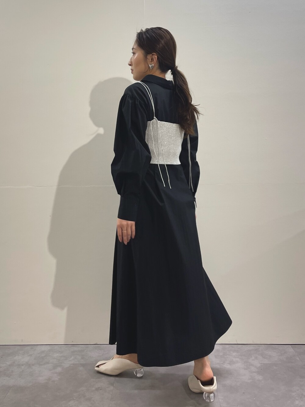 ホワイト系のパンプス、ブラック系のシャツワンピース、シルバー系のイヤリングを着用したレディースの冬コーディネートの4枚目の写真