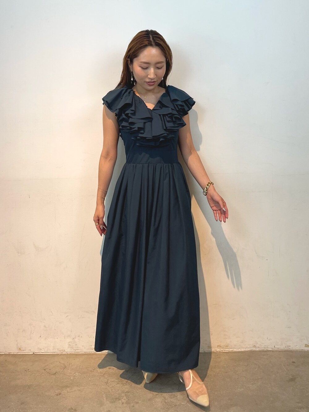 ベージュ系のパンプス、グリーン系のドレス、ゴールド系のピアス（両耳用）を着用したレディースの夏コーディネートの2枚目の写真