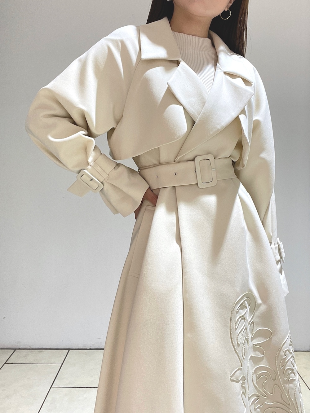 ホワイト系のトレンチコート、ベージュ系のサンダル、グリーン系のショルダーバッグを着用したレディースの冬コーディネートの10枚目の写真