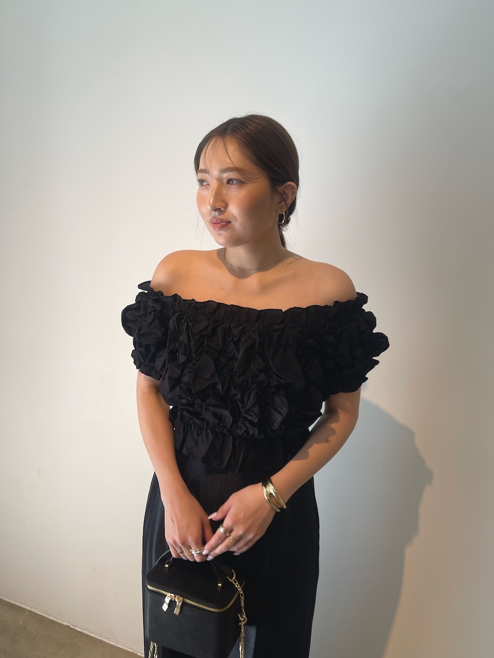 ブラック系のハンドバッグ、ゴールド系のパンプス、ブラック系のパンツドレスを着用したレディースの春コーディネートの9枚目の写真