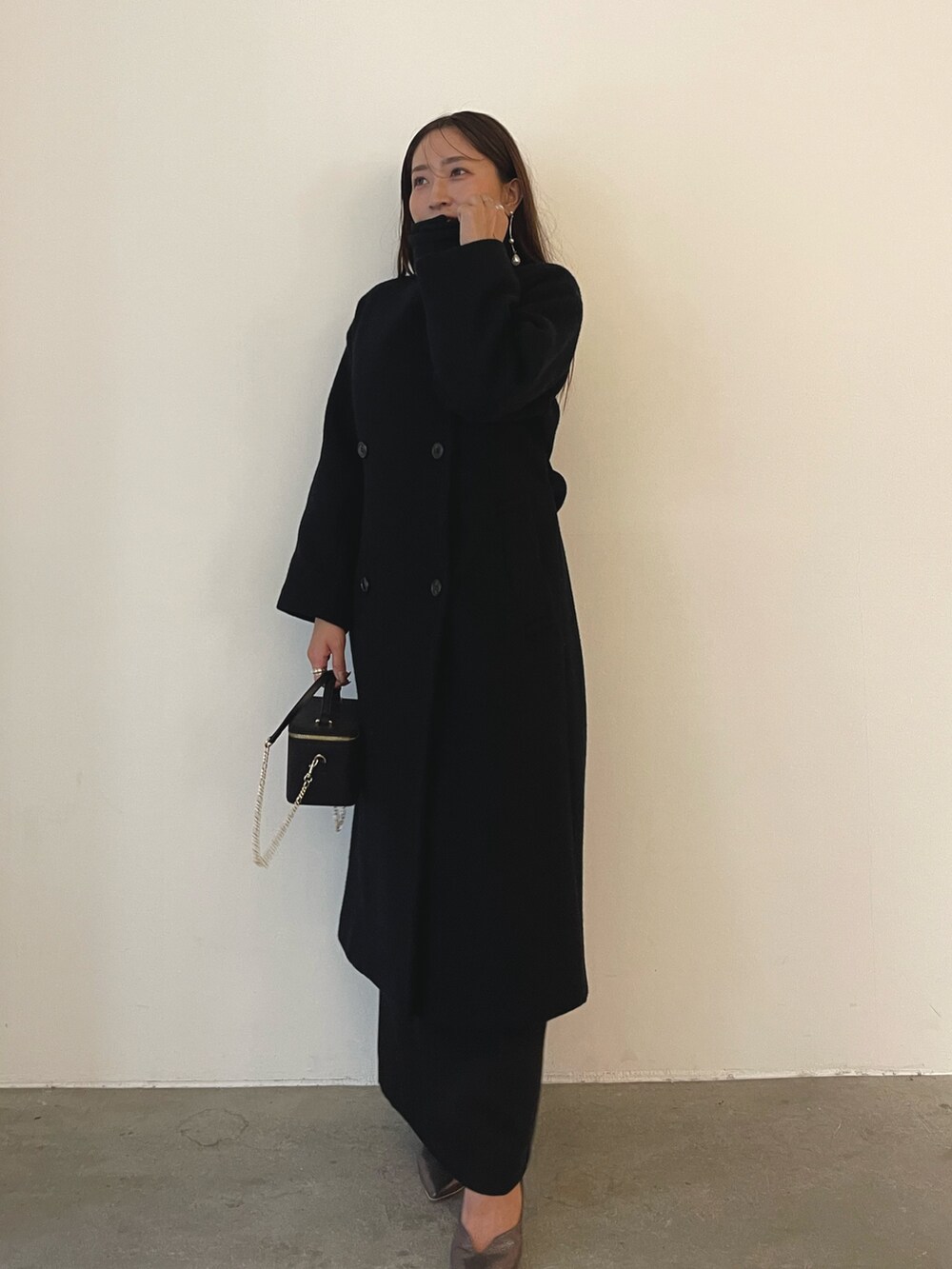 シルバー系のパンプス、ブラック系のハンドバッグ、ブラック系のドレスを着用したレディースの秋コーディネートの6枚目の写真