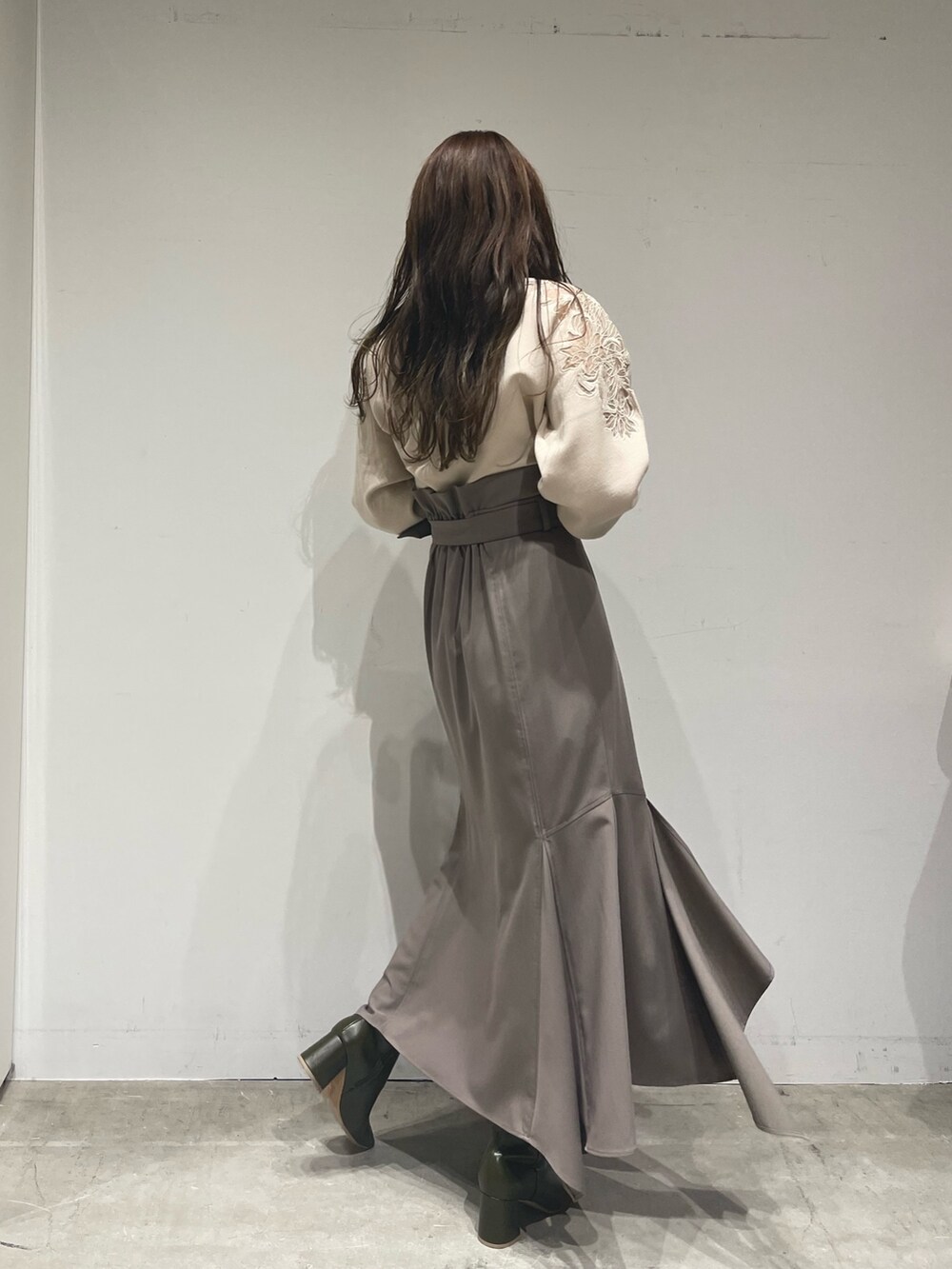 ホワイト系のニット/セーター、ブラウン系のスカート、ベージュ系のブーツを着用したレディースの冬コーディネートの4枚目の写真