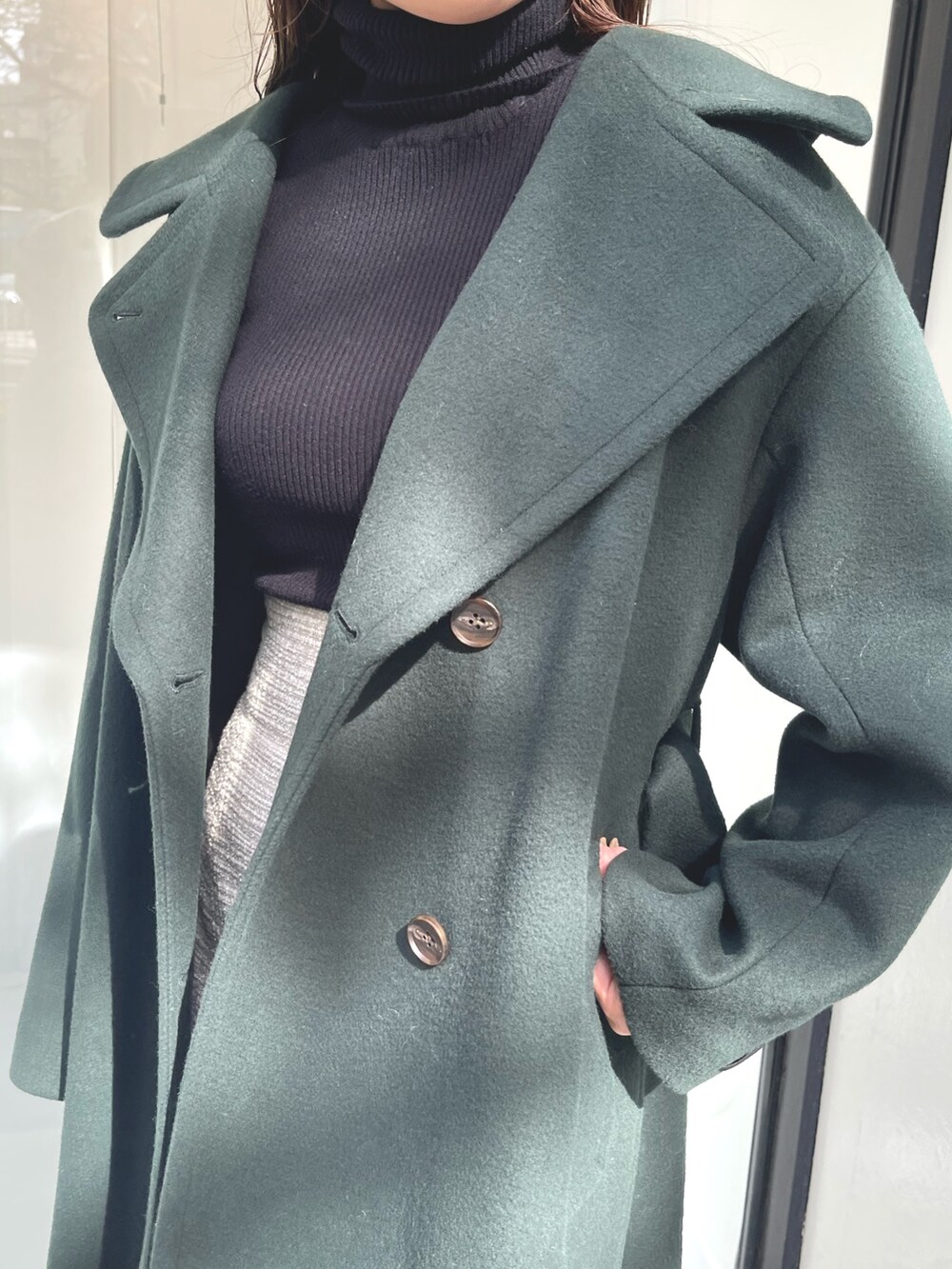 グリーン系のステンカラーコート、ブラック系のニット/セーター、ベージュ系のブーツを着用したレディースの秋コーディネートの7枚目の写真