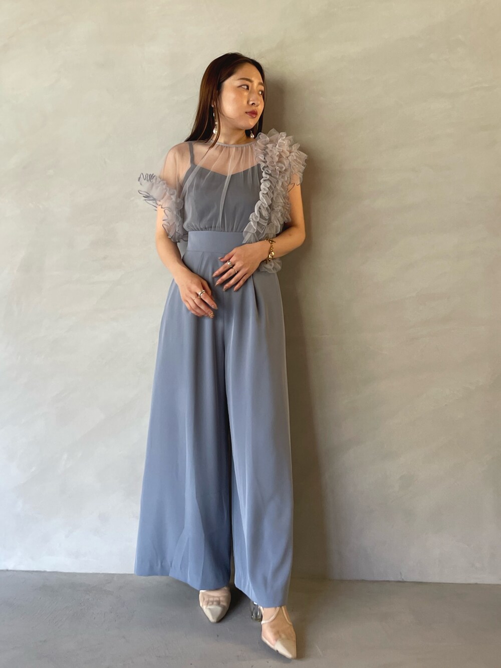 ブルー系のパンツドレス、ゴールド系のピアス（両耳用）を着用したレディースの夏コーディネートの3枚目の写真