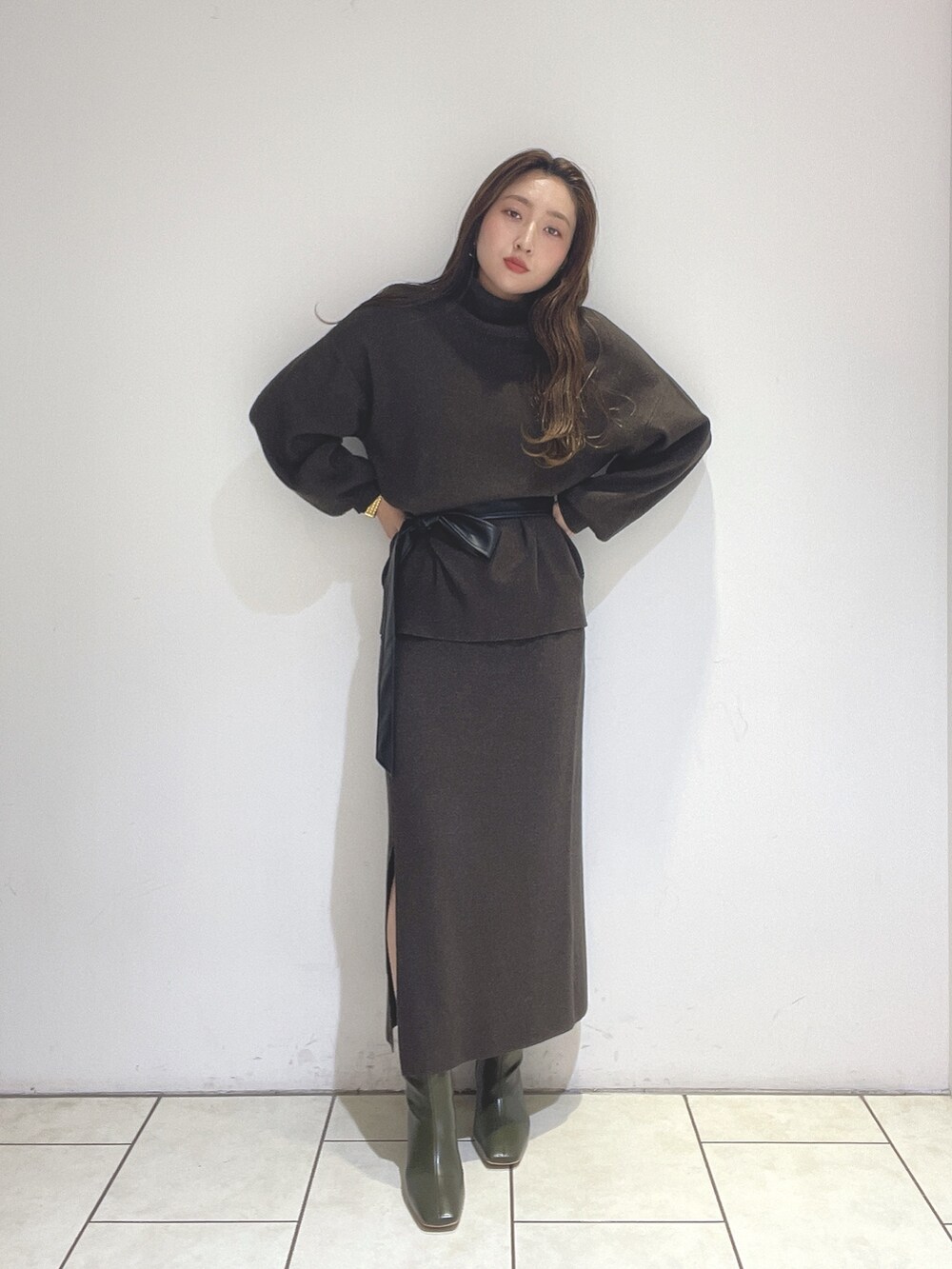 ブラウン系のニット/セーター、ブラウン系のスカート、グリーン系のブーツを着用したレディースの冬コーディネートの2枚目の写真