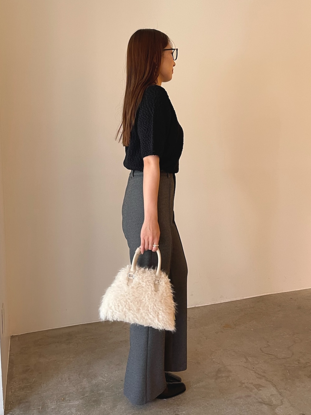 ホワイト系のボストンバッグ、ブラック系のブーツ、ブラック系のニット/セーターを着用したレディースの夏コーディネートの6枚目の写真