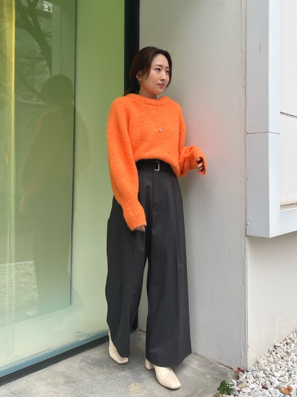 オレンジ系のニット/セーター、グレー系のその他パンツ、ホワイト系のブーツを着用したレディースの冬コーディネートの5枚目の写真
