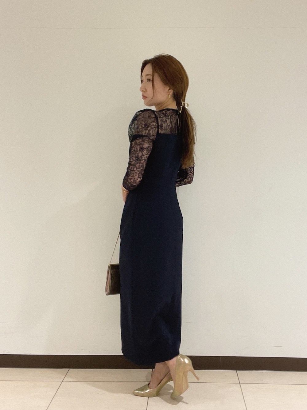 ゴールド系のハンドバッグ、ゴールド系のパンプス、ブルー系のドレスを着用したレディースの夏コーディネートの5枚目の写真